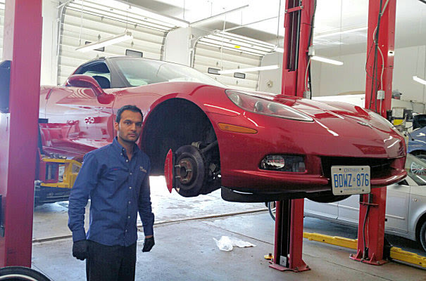 A Corvette up on a two post lift with its front wheel off