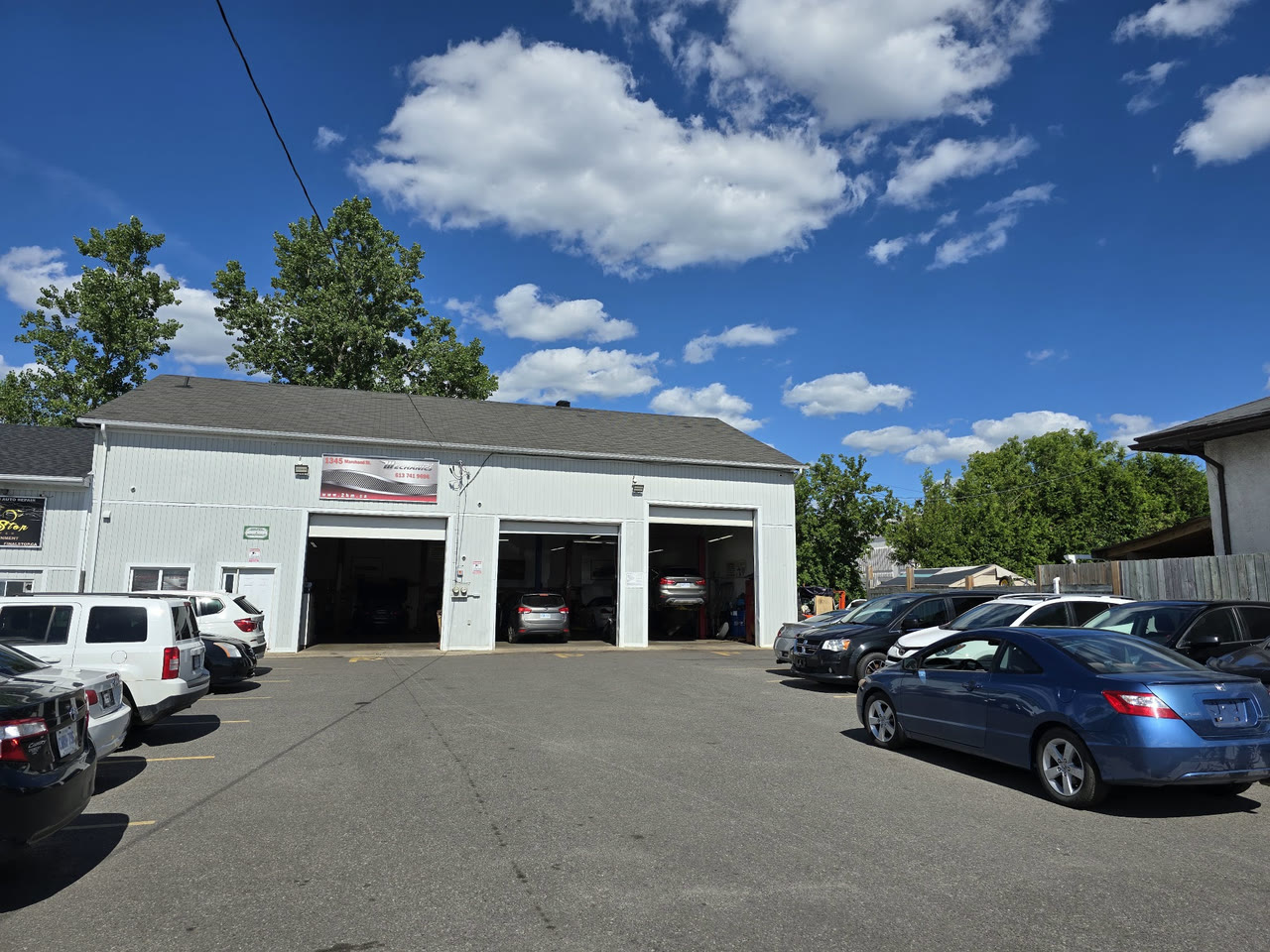 The shop at 1345 Marchand Street, three bay doors open under the 2 and 1/2 Mechanics sign