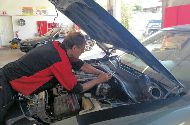 Leaning into an engine bay to reach the back of the motor